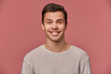 Wall Mural - Portrait of handsome young cheerful man wears in blank long sleeve, looks at the camera with happy expressions, stands over pink background.