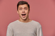 © timtimphoto - Photo of young scared guy in blank long sleeve, stands over pink background with wide open eyes and screaming, looks crazy and unhappy.