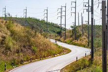 Wavy Road Along Mountain With Many Electricity Posts On Roadside