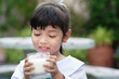 © Asada - Asian cute student girl drinking a glass of milk at home before going to school in the morning. The concept is healthy and intelligent kid concept.