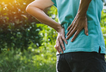 Closeup Hands Of Woman Touching Her Back Pain In Healthy Concept On Nature Background.