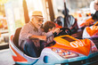canvas print picture - Grandfather and grandson having fun and spending good quality time together in amusement park. They enjoying and smiling while driving bumper car together.