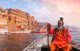 Indian Sadhu baba takes a boat ride on river Ganges overlooking the historic Varanasi city architecture at sunset