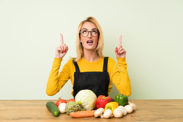 Young blonde woman with lots of vegetables pointing with the index finger a great idea