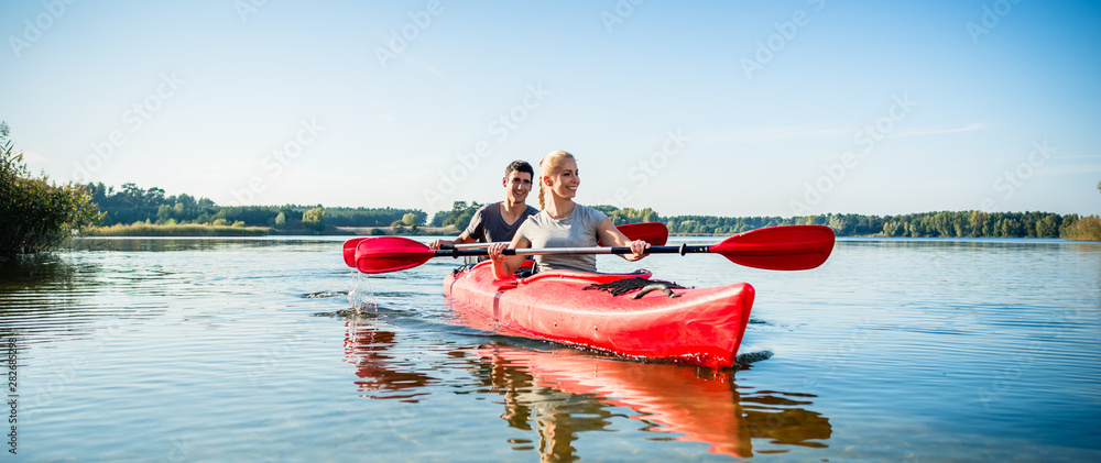 Happy couple kayaking on lake - obrazy, fototapety, plakaty 