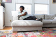 © Adam Crowley - Woman working on her laptop sitting on couch