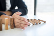 © Ngampol - Risk and Strategy in Business, Image of hand stopping falling collapse wooden block dominoes effect from continuous toppled block, prevention and development to stability
