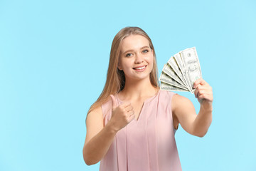 Canvas Print - Happy woman with money showing thumb-up gesture on color background