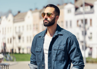 Portrait of successful multicultural businessman wearing sunglasses standing at the street