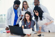 © gorynvd - Group of young multi national doctors during working with laptop in the conference room.