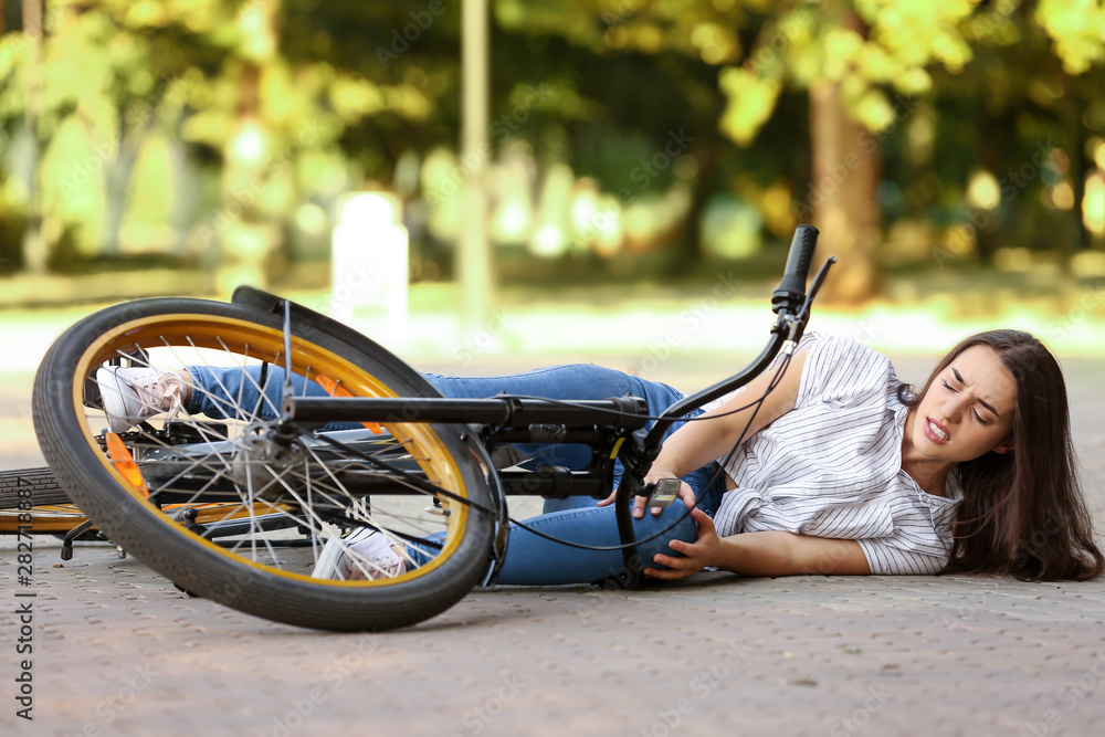 Young woman fallen off her bicycle outdoors