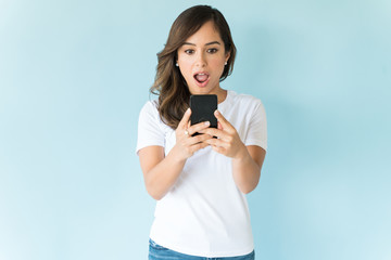 Wall Mural - Surprised Female Using Smartphone Over Colored Background