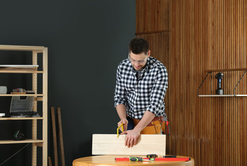 Poster - Handsome working man using hand saw indoors. Home repair