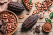 Flat lay composition with cocoa beans, chocolate pieces and pods on wooden table