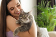 © New Africa - Young woman with cute cat at home, space for text. Pet and owner
