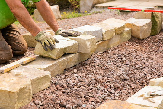 Fototapete - Man landscaping with natural stones -  Building of a dry stone wall