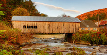 A Historic Yellow Wooden Covered Bridge Crosses A Small Stream In Autumn In Vermont