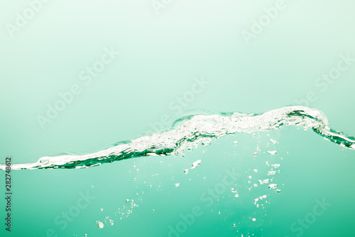 Fotomural transparent pure water with splash and bubbles on green background