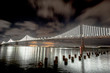 San Francisco-Oakland Bay Bridge lit at night reflecting in water