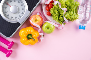 Healthy lifestyle, food and sport concept. Top view of athlete's equipment Weight Scale measuring tape blue dumbbell, sport water bottles, fruit and vegetables on pink pastel background.