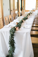Garland Of Greenery On Table At Wedding Reception, White Table Cloth, Minimal And Modern Wedding Flowers