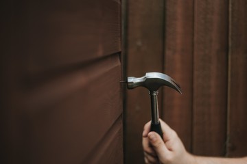 Sticker - Closeup shot of a hammer tool on a wooden brown background