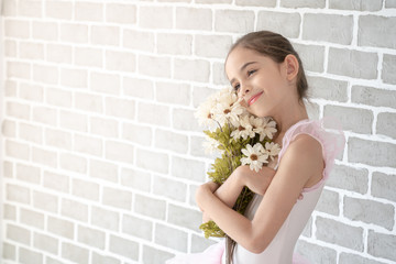 cute little young preschool girl ballerina dance in pink leotard and tutu holding flowers bouquet in