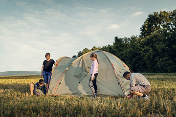 family set up tent camp at sunset, beautiful summer landscape. tourism, hiking and traveling in natu