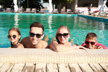 Wall Mural - Happy family in swimming pool on summer day