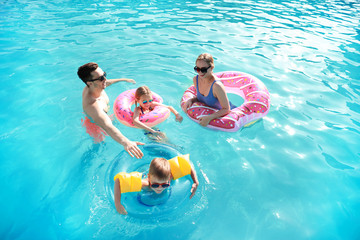 Wall Mural - Happy family swimming in pool on summer day