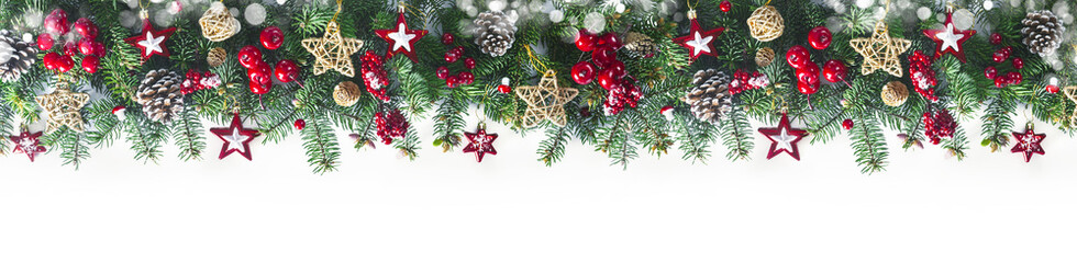 Festive Christmas border, isolated on white background. Fir green branches are decorated with gold stars, fir cones and red berries, banner format.