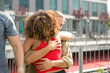 © Mangostar - Caucasian man and black woman embracing each other outside. Close friends meeting on outdoor building terrace, hugging and greeting each other. Friendship and trust concept