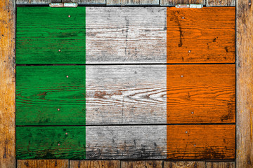 Wall Mural - National flag of Ireland on a wooden wall background.The concept of national pride and symbol of the country.Flag painted on a wooden fence with metal nails.