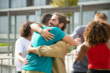 Happy guys in casual hugging each other. Close friends meeting on outdoor building terrace, embracing and greeting each other. Bonding concept
