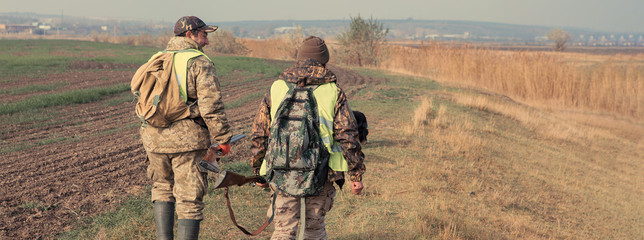 Hunters with a german drathaar and spaniel, pigeon hunting with dogs in reflective vests	