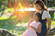 © prachid - Asian mother and little daughter playing together outdoors.Happy family in mother's day concept,I Love you best mom.Mum and adorable little cute child greeting ,proud and hug in meadow.