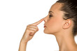 © vladimirfloyd - young woman touches her nose with her finger on a white background