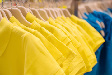 Wall Mural - Shirts of yellow color on hangers in shop, selective focus