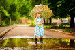 © Svetlana - happy child girl in dress with an umbrella and rubber boots in puddle on summer walk