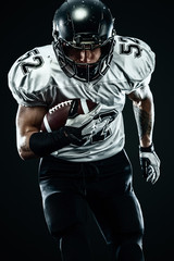 Wall Mural - American football sportsman player in helmet isolated run in action on black background. Sport and motivation wallpaper.