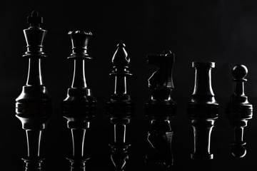 Chess figures on dark black background close up