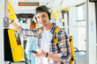 © Iryna - Young man is standing in a bus with headset on his head and listening to the music.