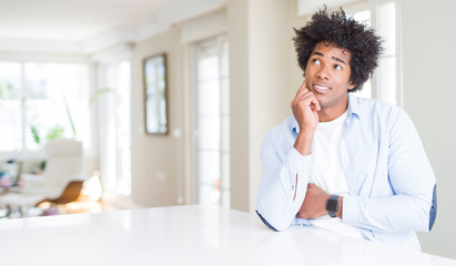 Canvas Print - African American man at home with hand on chin thinking about question, pensive expression. Smiling with thoughtful face. Doubt concept.