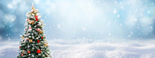 Beautiful Festive Christmas Snowy Background. Christmas Tree Decorated With Red Balls And Knitted Toys In Forest In Snowdrifts In Snowfall Outdoors, Banner Format, Copy Space.