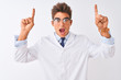 © Krakenimages.com - Young handsome sciencist man wearing glasses and coat over isolated white background smiling amazed and surprised and pointing up with fingers and raised arms.