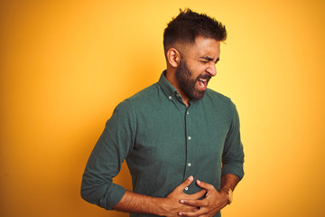 Wall Mural - Young indian businessman wearing elegant shirt standing over isolated white background with hand on stomach because indigestion, painful illness feeling unwell. Ache concept.