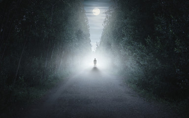 silhouette of a man in a dark and foggy forest