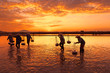 Woman workers collecting freshly harvested salt into baskets at sunrise in Hon Khoi salt field, Nha Trang Province, Vietnam
