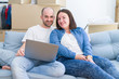 © Krakenimages.com - Young couple sitting on the sofa at new home using computer laptop, smiling happy for moving to a new apartment