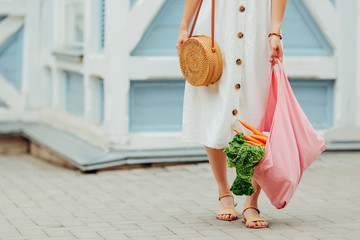 Wall Mural - Young woman holding pink cotton grocery bag with vegetables. Reusable eco bag for shopping. Zero waste concept.